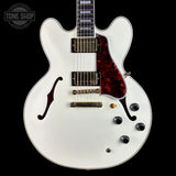 White electric guitar with a red tortoiseshell pickguard on a black background, featuring 'Tone Shop' branding.