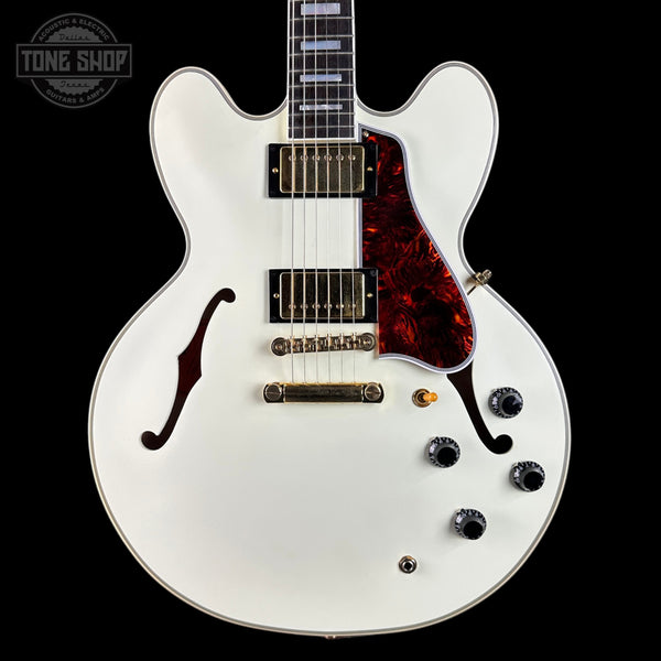 White electric guitar with a red tortoiseshell pickguard on a black background, featuring 'Tone Shop' branding.