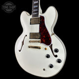 White electric guitar with a red pickguard on a black background, featuring 'Tone Shop' branding.