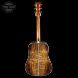 Back view of a wooden acoustic guitar with 'Tone Shop' logo.