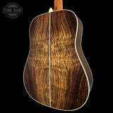 Close-up of a wooden acoustic guitar with a visible brand logo in the corner.