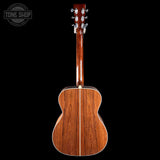 The back of an acoustic guitar with a glossy reddish-brown wood finish, shown against a solid black background. A circular 'TONE SHOP' watermark is visible in the top-left corner.