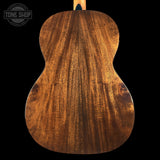 Back view of a wooden acoustic guitar with 'Tone Shop' logo.