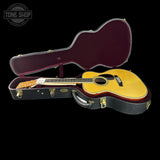 Acoustic guitar in an open case with 'Tone Shop' logo in the corner.