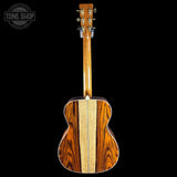 Back view of a wooden acoustic guitar with a visible brand logo in the corner.