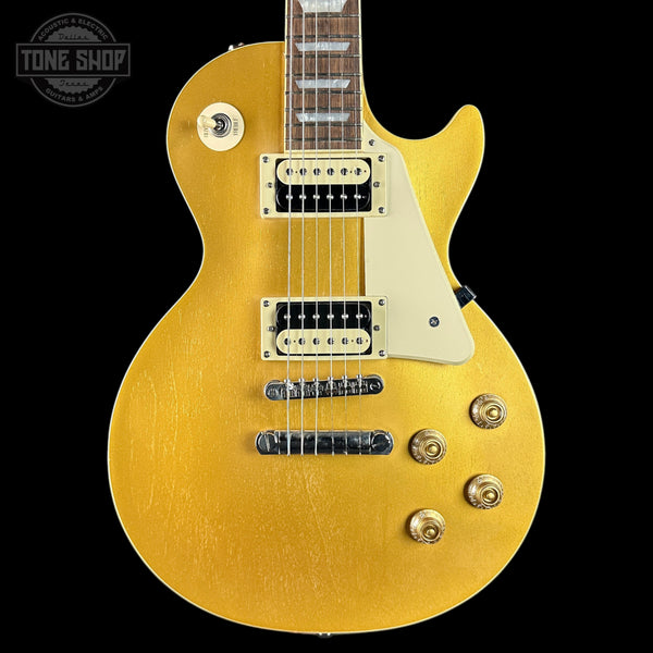 Gold electric guitar with a 'Tone Shop' logo in the corner