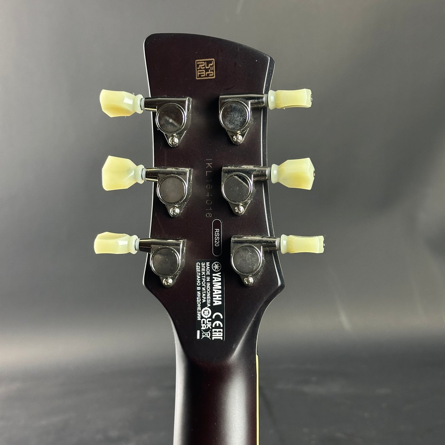 Guitar headstock with tuning pegs on a dark background