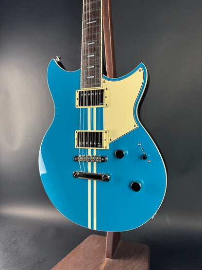 Blue electric guitar with a gold pickguard on a dark background