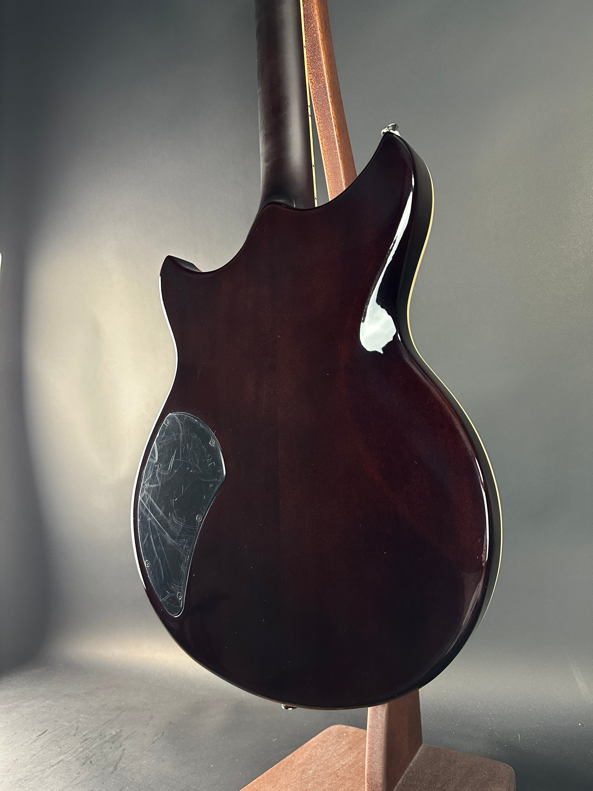 Close-up of a dark brown guitar body on a gray background