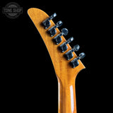 Close-up of a guitar headstock with tuning pegs on a black background, featuring the Tone Shop logo.