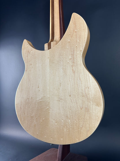 Close-up of a guitar body with a natural wood finish against a dark background