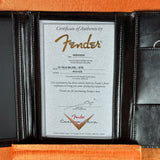 A Fender Certificate of Authenticity document displayed inside an open black leather portfolio folder, with orange felt lining visible around the edges.