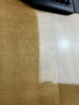 Close-up of a textured surface with a white area and a black object on the left.