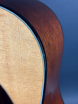 Close-up of an acoustic guitar's soundhole and wooden body against a blue background