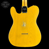 The back of a yellow-finish electric guitar with a black plate and visible wear/scuffs on the body, shown against a black background with a Tone Shop watermark in the top left.