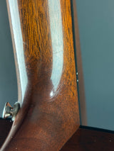 Close-up of a wooden gun stock with a visible scratch on a gray background