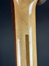 Close-up of a wooden guitar neck with a dark background