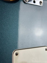 Close-up of a guitar with metallic hardware on a blue background