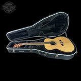 Acoustic guitar in a hard-shell case with 'Tone Shop' logo in the corner.