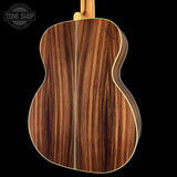 Close-up of a wooden acoustic guitar on a black background with 'Tone Shop' logo.