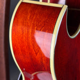 Close-up of a red acoustic guitar with a visible grain pattern.