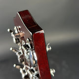 Close-up of a guitar headstock with tuning pegs on a blurred background