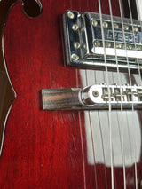Close-up of a guitar's neck and fretboard with a red finish