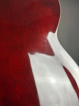 Close-up of a red guitar with a white pickguard on a gray background
