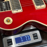 Red electric guitar on a digital scale displaying weight