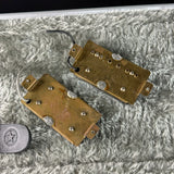 Two brass-colored metal components on a textured gray surface with a small round object featuring a star symbol in the bottom right corner.