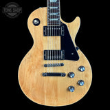 Electric guitar with a natural wood finish on a black background, featuring the 'Tone Shop' logo.