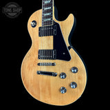 Electric guitar with a natural wood finish on a black background, featuring the Tone Shop logo.