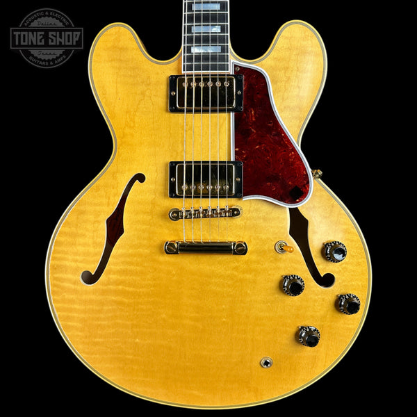 A classic electric guitar with a natural flamed maple top, red tortoiseshell pickguard, and black hardware, shown against a solid black background with a Tone Shop watermark in the top left corner.