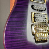 Close-up of a purple electric guitar with gold hardware on a gray background