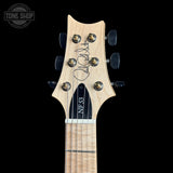 Close-up of the headstock of a six-string electric guitar against a solid black background. The headstock features a light natural wood finish, a black trapezoidal neckplate with 'NF3' printed on it, and six black tuning pegs with gold-toned screws.