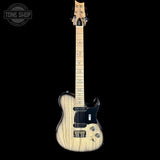 A natural wood electric guitar with a black pickguard and hardware, shown vertically against a solid black background. A Tone Shop watermark is visible in the top-left corner.