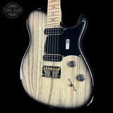 A double-cutaway electric guitar with a natural wood grain finish, black pickguard, and black neck, shown against a solid black background. A Tone Shop watermark is visible in the top-left corner.