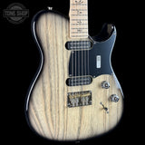 A close-up of an electric guitar body with a natural wood grain finish, black pickguard, and silver hardware, shown against a black background with a Tone Shop watermark in the top left corner.