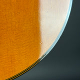 Close-up of a guitar's soundboard and back, showing wood grain and finish.