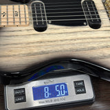 A close-up of a guitar body being weighed on a digital scale, with the scale displaying 8.50 lbs.