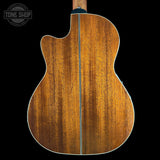 Back view of a wooden acoustic guitar with 'Tone Shop' logo in the corner.