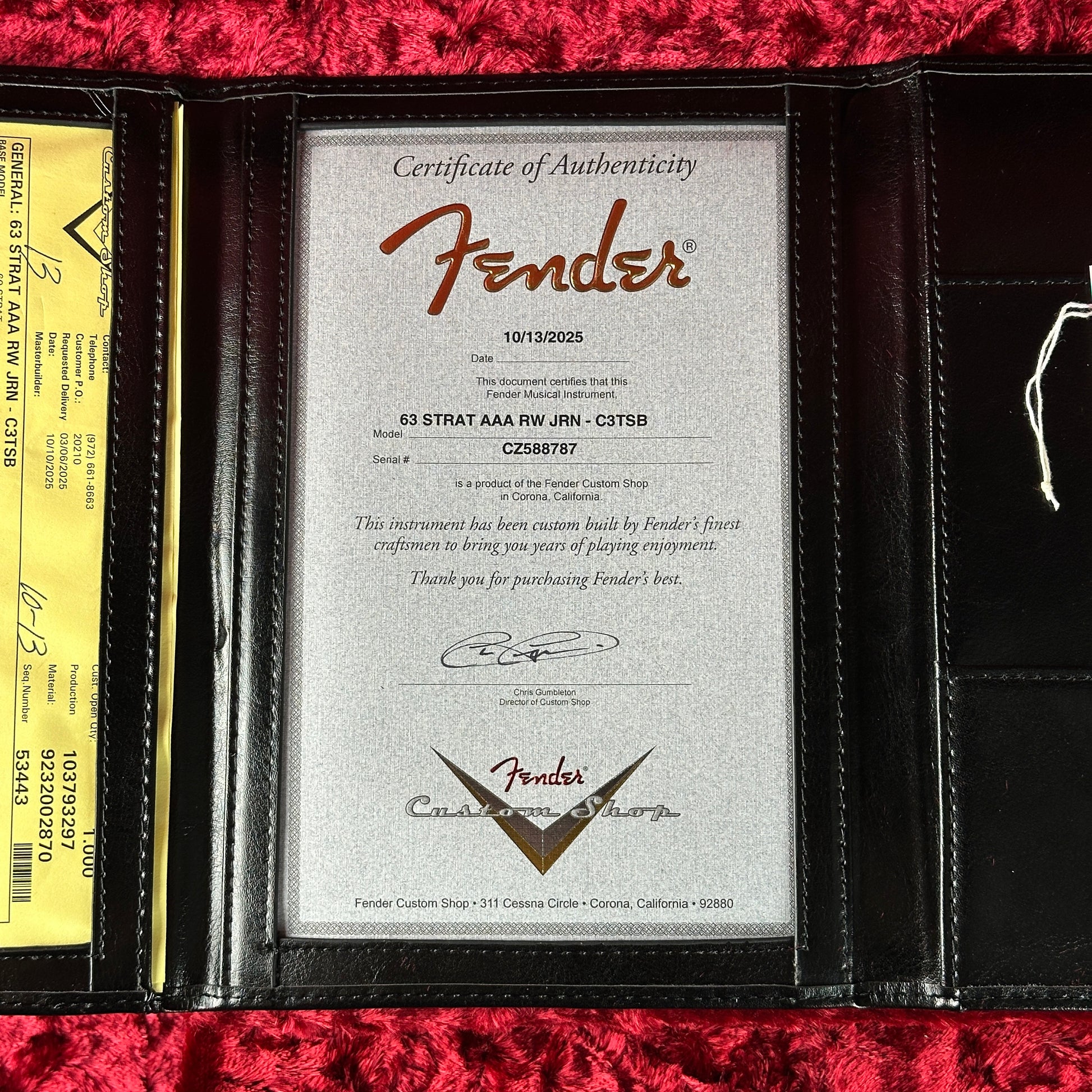 Fender certificate of authenticity in a black leather holder on a red textured surface