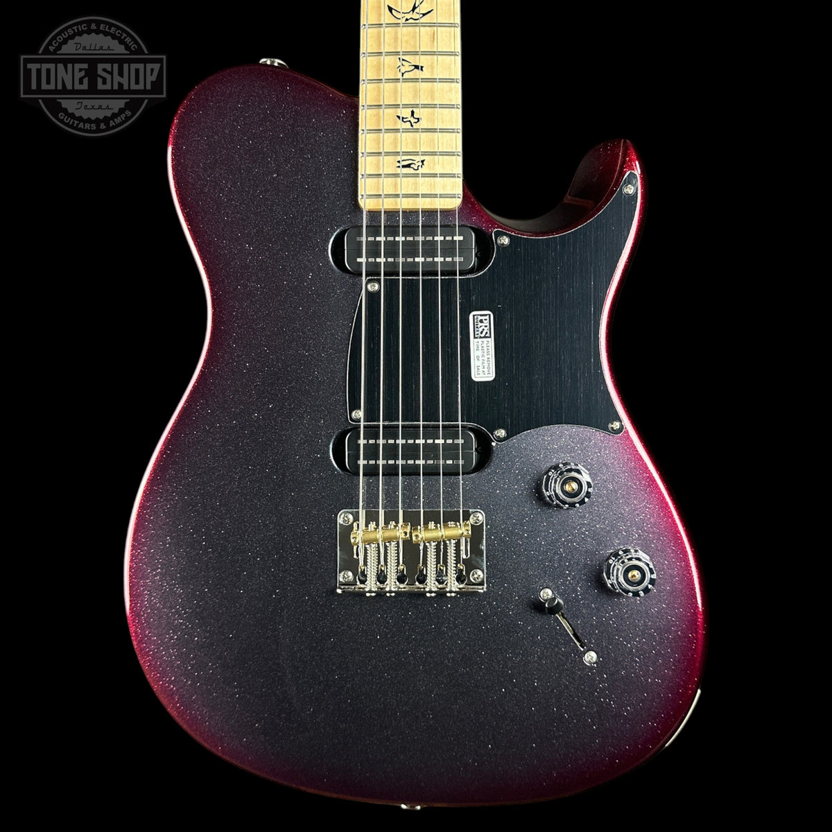 A close-up of a Fender Telecaster-style electric guitar body with a dark purple-to-red glitter finish, black pickguard, maple neck, and gold hardware, shown against a black background with a Tone Shop watermark in the upper left.