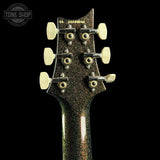 Close-up of the headstock of a guitar with a black glitter finish, cream-colored tuning pegs, and gold-toned screws, set against a solid black background.