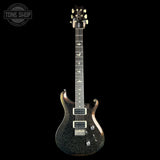 A black electric guitar with a glittery gold and silver finish, featuring white hardware and a dark fretboard, shown against a solid black background with a Tone Shop watermark in the top left corner.