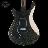 Close-up of the back of an electric guitar body with a black glitter finish, black pickguard, and a light pink side strip, shown against a black background with a Tone Shop watermark in the top left.