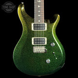 A green glitter electric guitar with a dark wood neck, chrome hardware, and a black background. A Tone Shop watermark is visible in the top left corner.