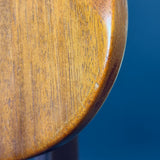 Close-up of a wooden stool seat against a blue background