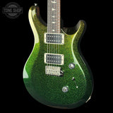 A green glitter electric guitar with a dark wood neck, dual humbucker pickups, and chrome hardware, shown against a solid black background with a Tone Shop watermark in the top left corner.