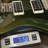 Close-up of an electric guitar body resting on a digital scale displaying 7.158 oz, with the scale showing brand text 'Kingsplace'.